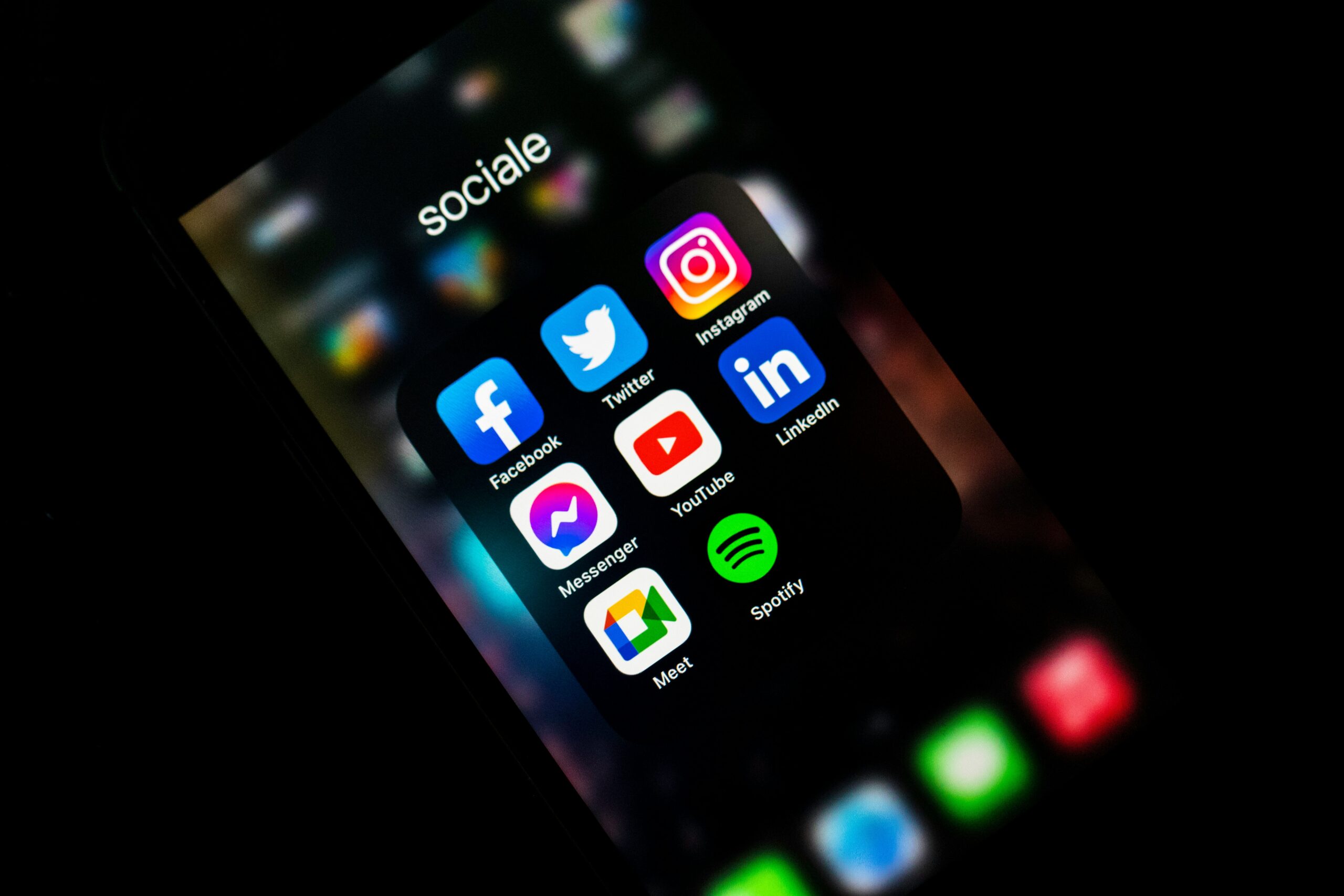 Popular social media apps such as Facebook, Instagram, LinkedIn, YouTube, and Twitter are displayed on a smartphone screen.